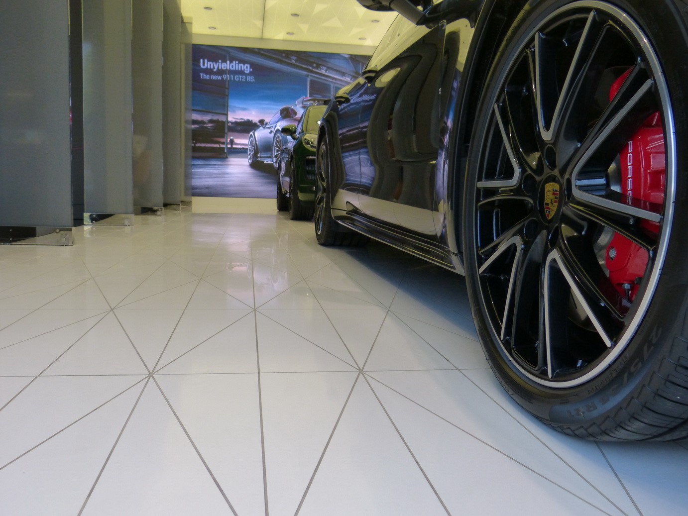 Automobil Porsche - detail pneu a ráfku na podlaze Taurus Black od Technistone